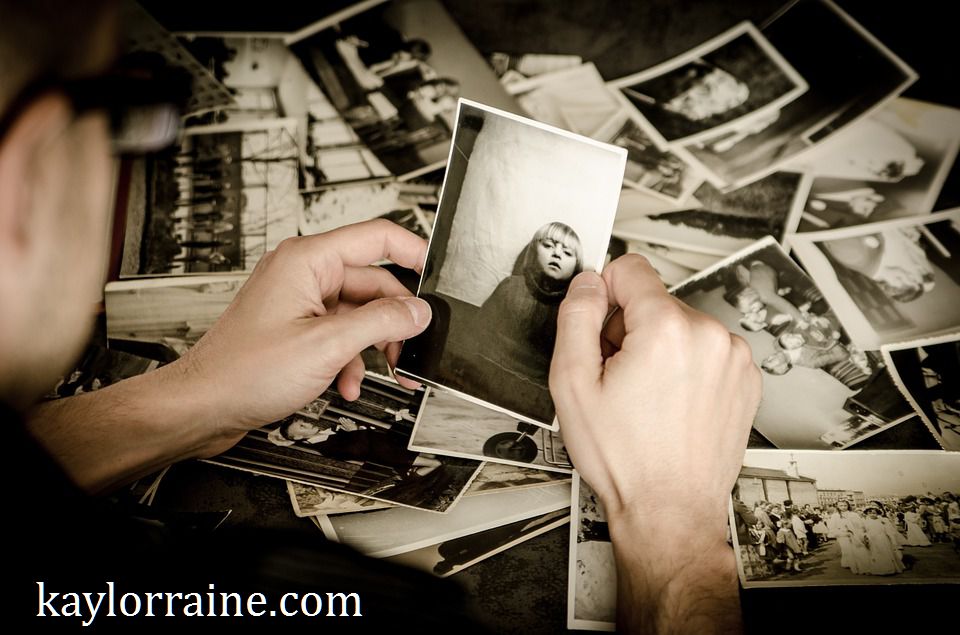 hands holding photograph with many pictures in the background