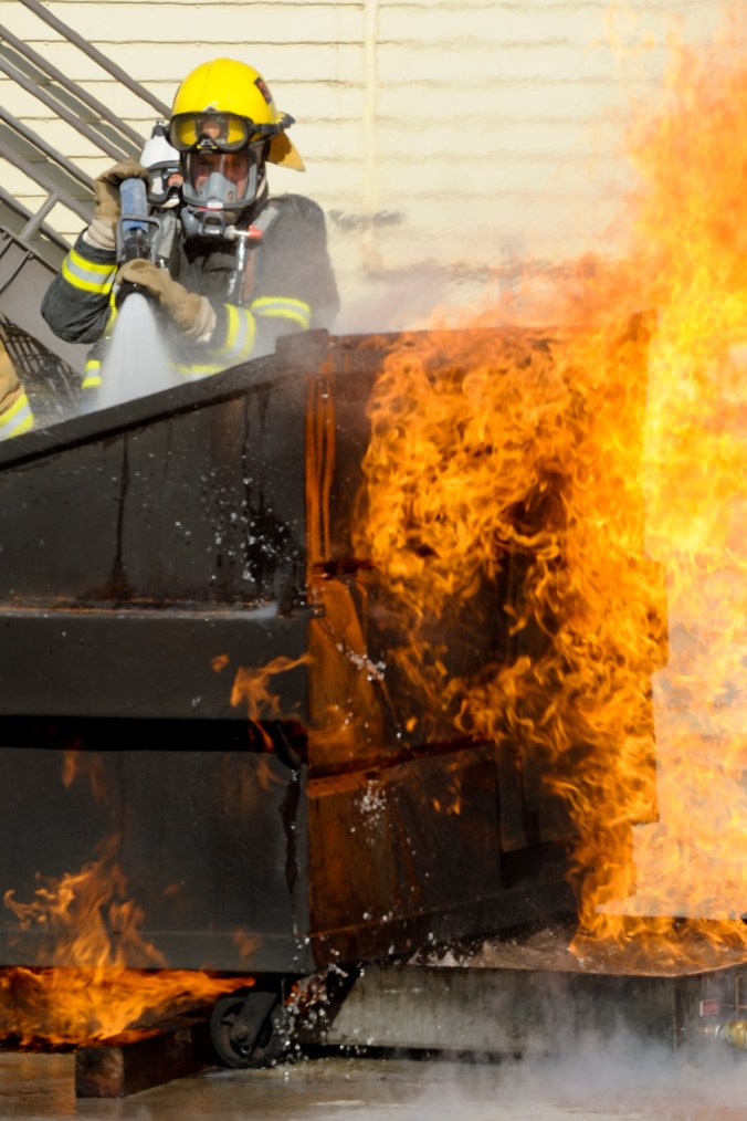 dumpster fire with fireman
