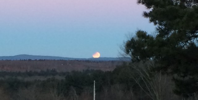 setting eclipse moon near a small mountain